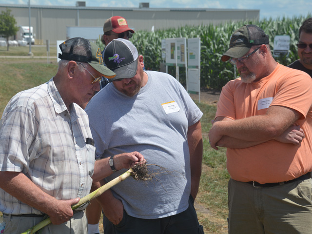 Charles Jacobi (left), Josh Jacobi (center) and Jeremy Amos check out corn root develop this summer at a research plot during a Precision Planting field day in Pontiac, Illinois. (DTN/Progressive Farmer photo by Matthew Wilde)